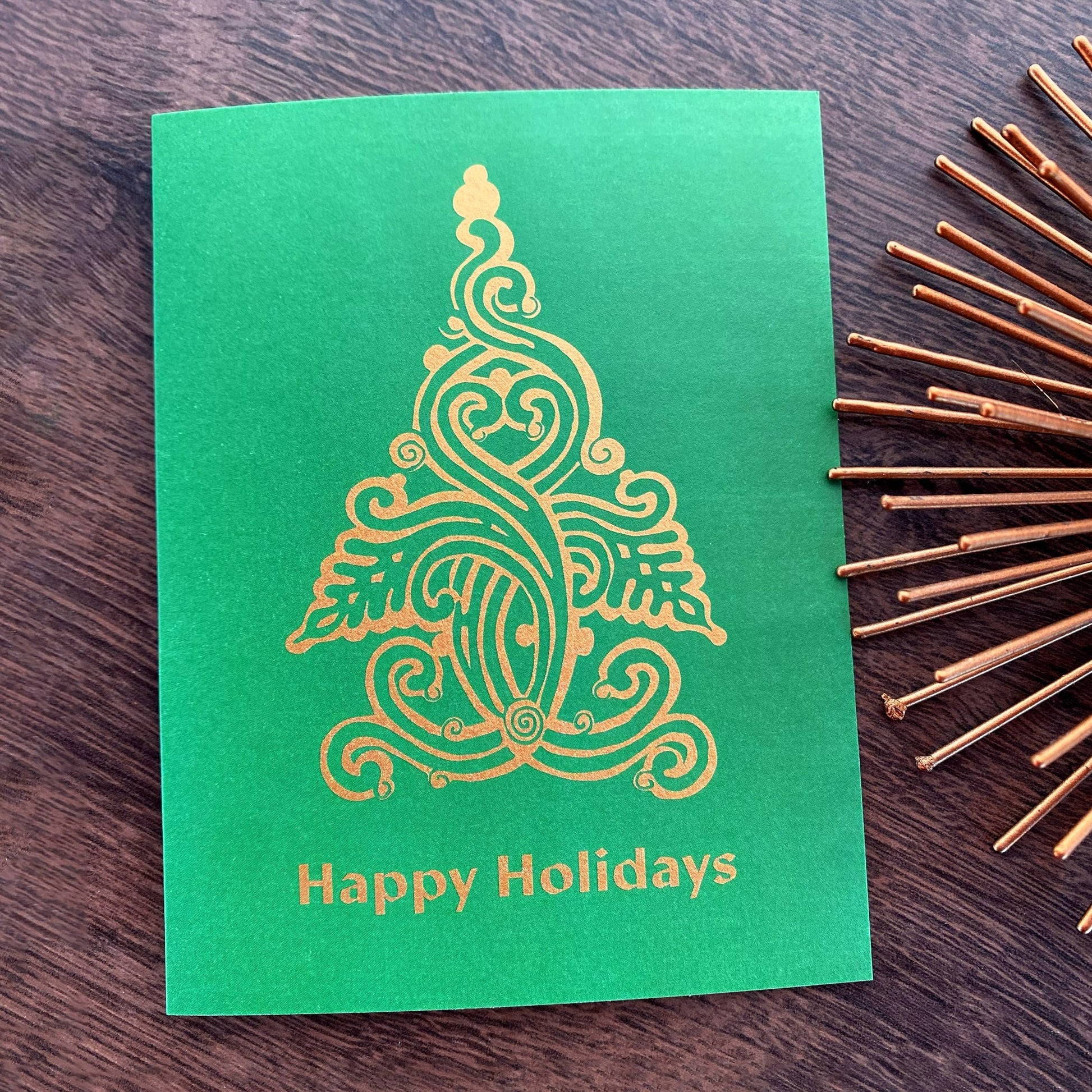 Green Christmas folk tree design on holiday card that reads "Happy Holidays" and is designed by artist Ariadne Kritonos.