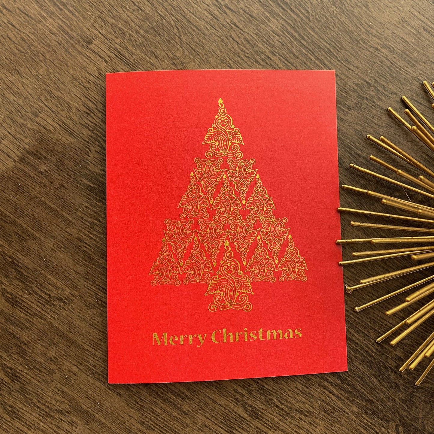 Red Christmas folk tree design on holiday card that reads "Merry Christmas" and is designed by artist Ariadne Kritonos.